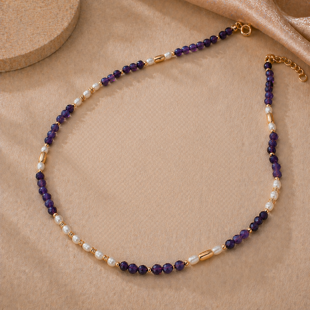 Amara pearl amethyst necklace with purple beads and vintage gold details on warm fabric