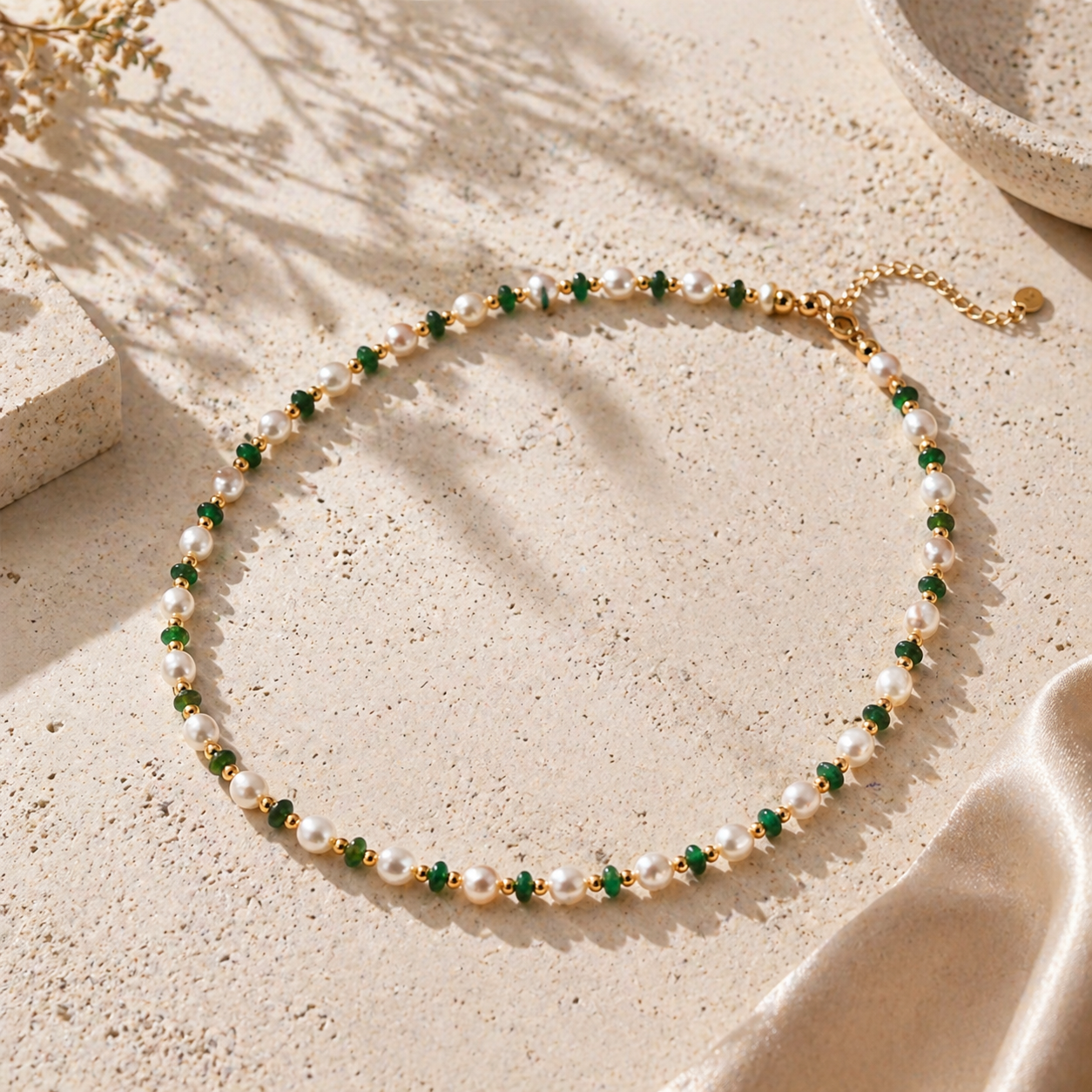Emerald pearl beaded necklace displayed on a warm neutral stone surface