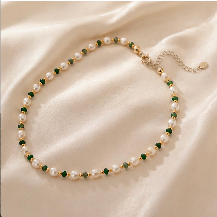 Emerald pearl beaded necklace with green gemstone beads and luminous pearls on soft fabric