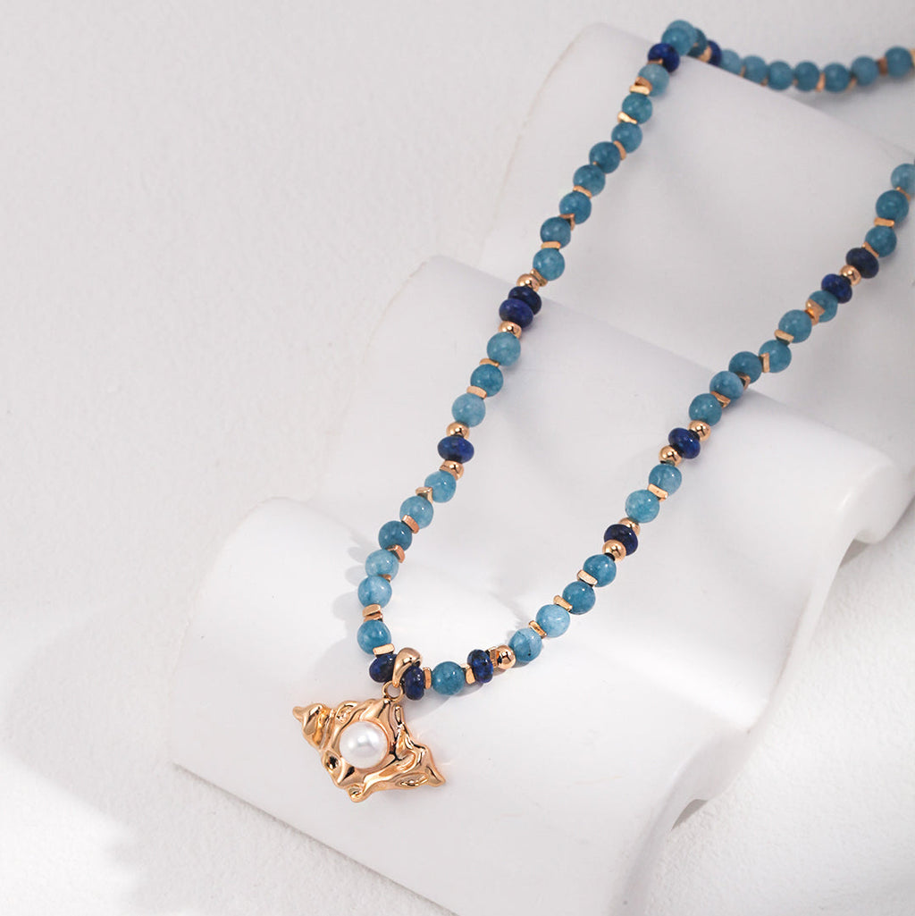 Lapis lazuli pearl sculptural necklace displayed on a white jewelry stand